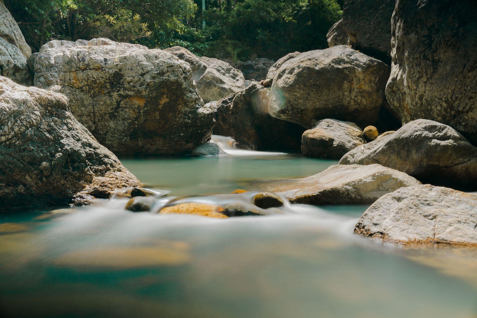 Turquoise water pooling between smooth boulders in a secluded natural swimming hole